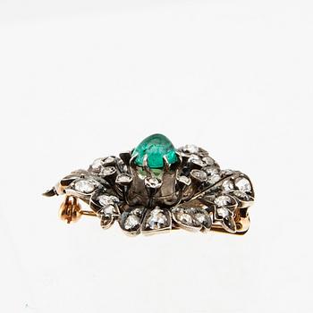 A 14K gold brooch set with a cabochon-cut emerald and old-cut as well as rose-cut diamonds.