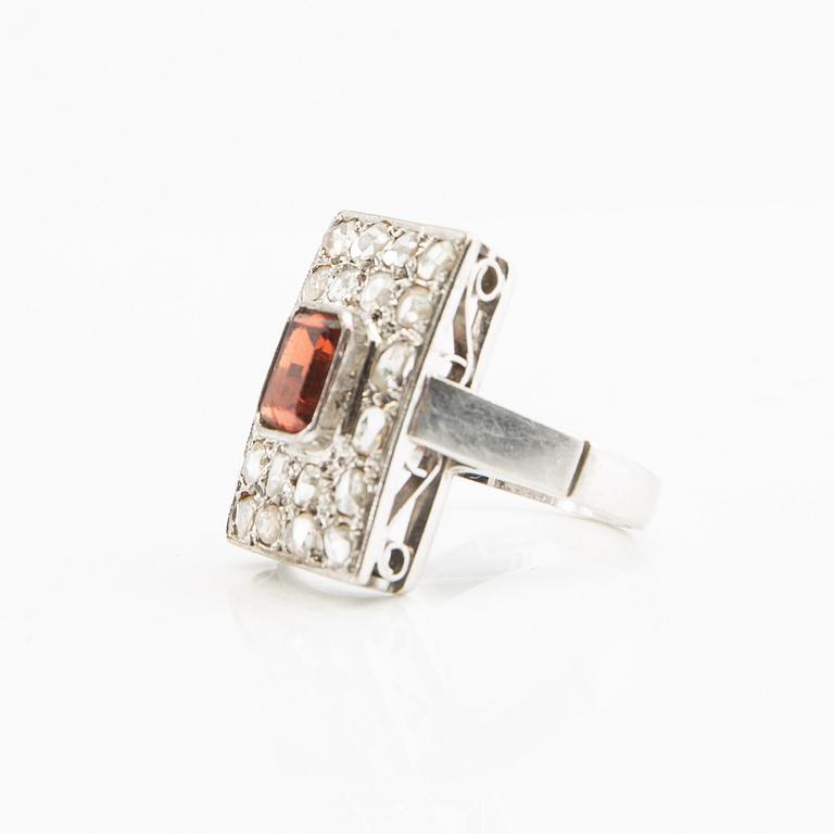 Ring, 18K white gold with a red stone (possibly garnet) and diamonds.