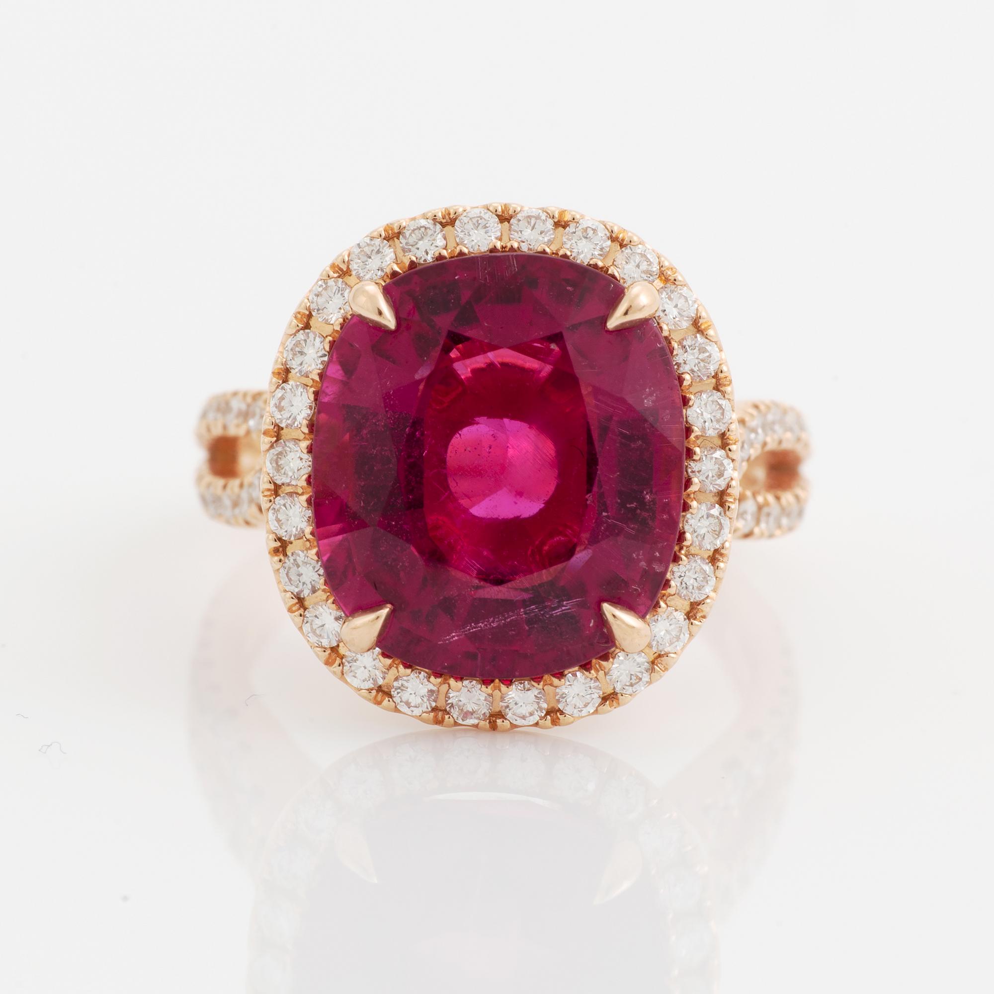An 18K gold ring set with a faceted pink tourmaline and round brilliant-cut diamonds.