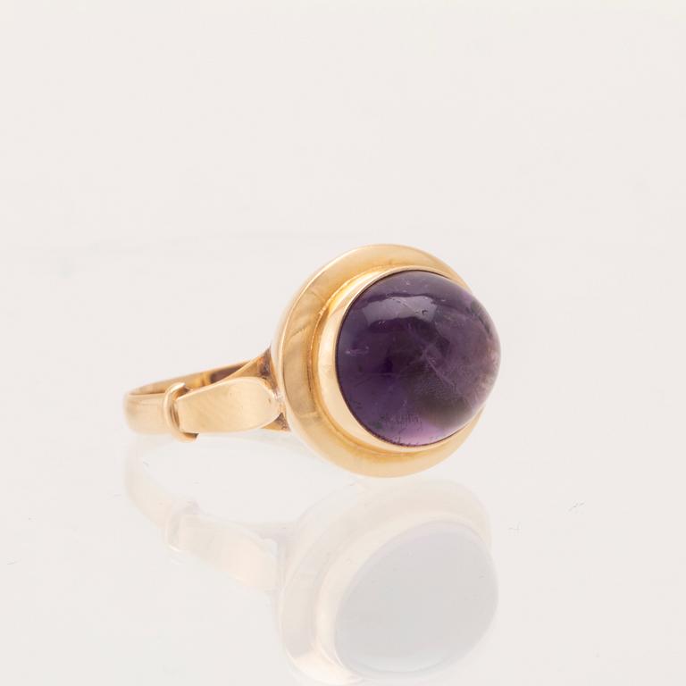 An 18K gold ring set with a cabochon-cut amethyst.