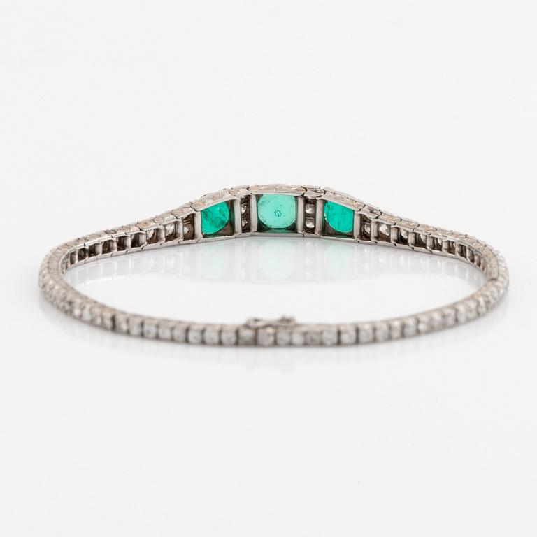 A platinum bracelet set with emeralds and round brilliant-cut diamonds.