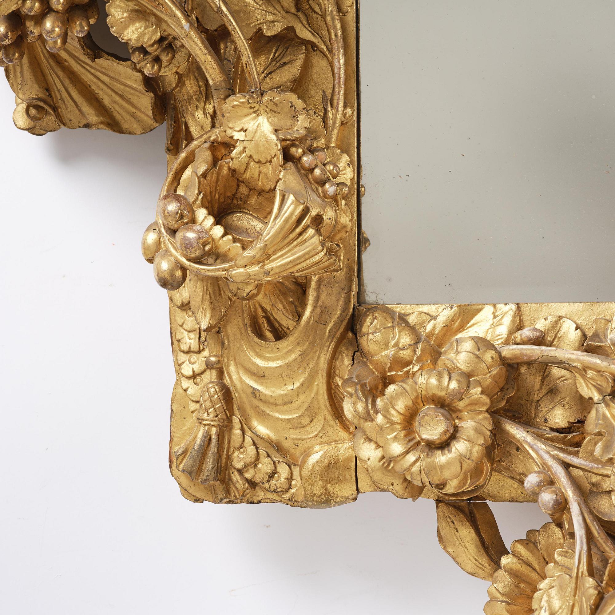 A presumably Dutch Louis XIV carved giltwood frame with mirror glass, in the style of Jean Le Pautre, late 17th century.