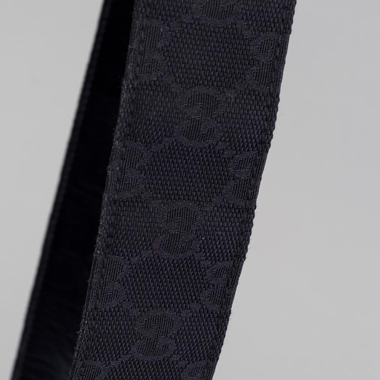 A blach monogram belt by Gucci.