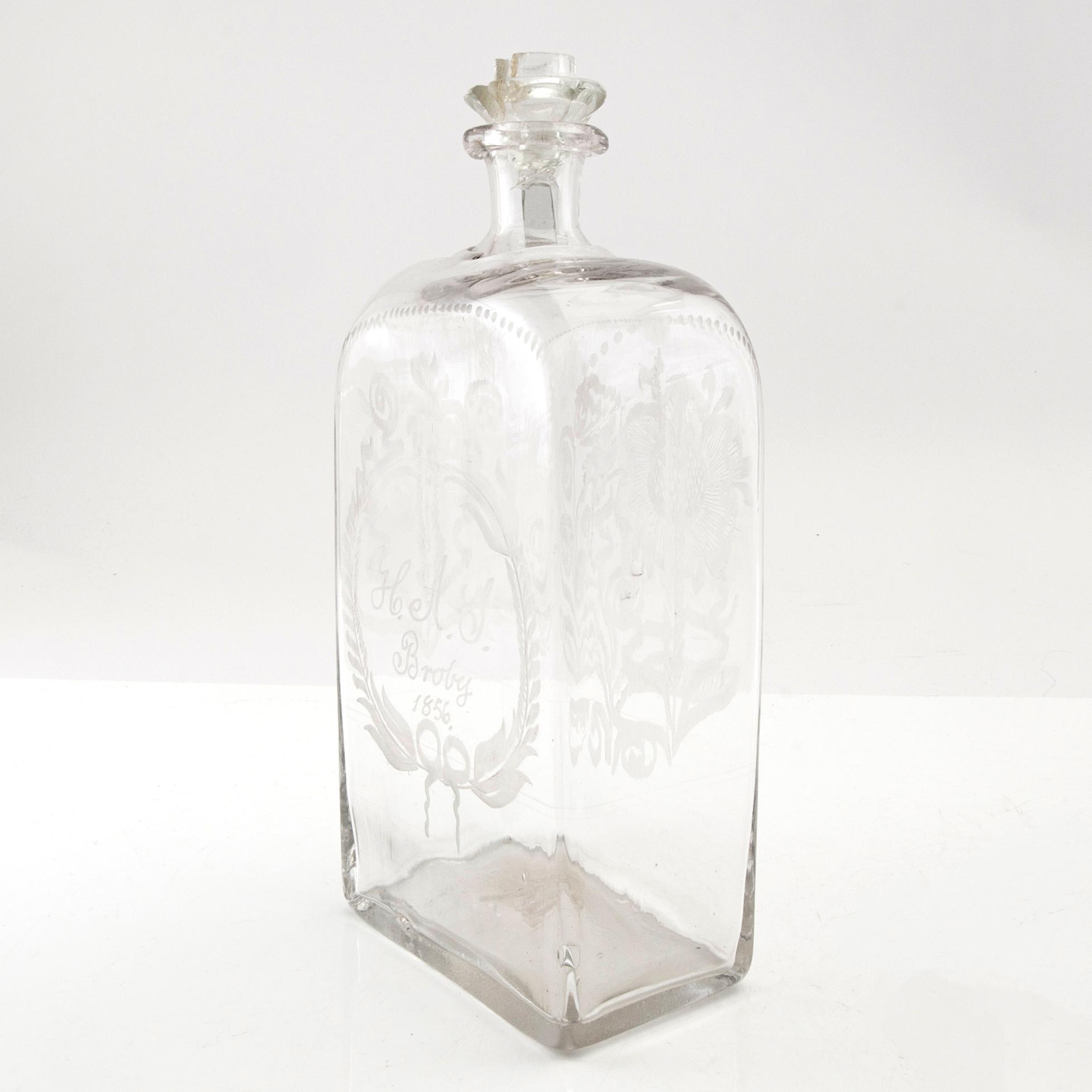 Brännvinsflaska, glas. Daterad Broby 1856.