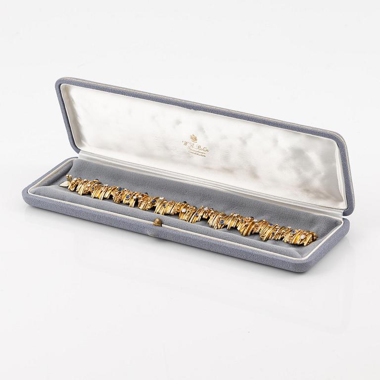 An 18K gold bracelet set with round brilliant-cut diamonds and cabochon-cut sapphires.
