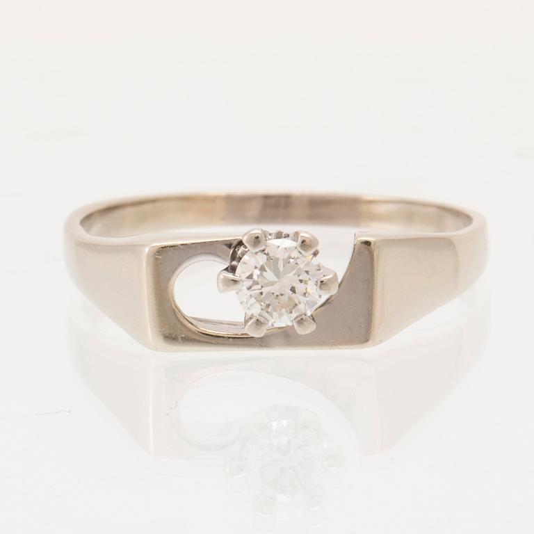 An 18K white gold solitaire ring set with a round brilliant-cut diamond.