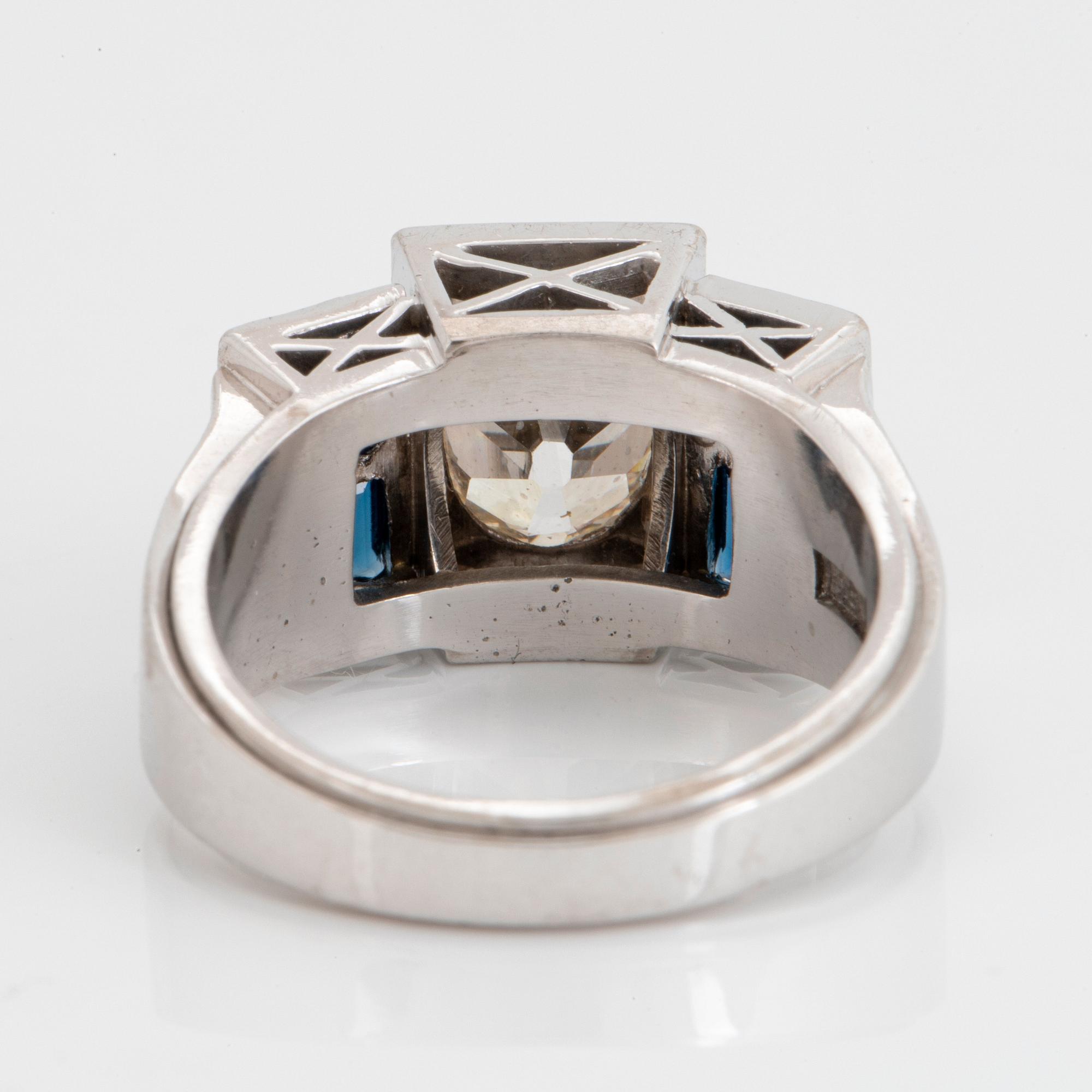 An 18K white gold ring set with an old-cut dimond weight ca 1.50 cts and step-cut sapphires.