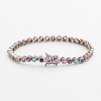 Rannekoru, 18K valkokultaa ja monivärisiä kiviä.