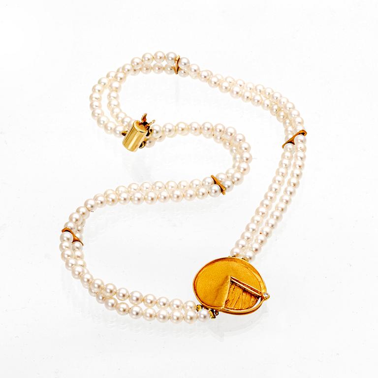 A necklace of cultured pearls and pendant in 18K gold with a brilliant cut diamond.