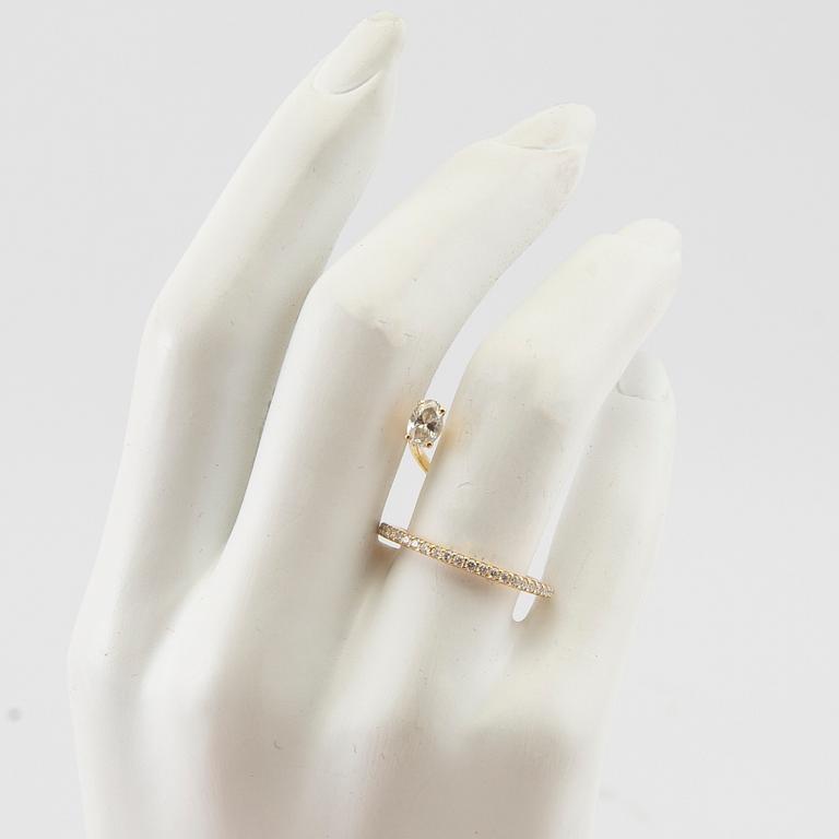 An 18K gold ring set with an oval cut and round brilliant cut diamonds by LWL Jewelry.