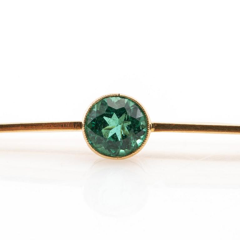 Brosch 18K guld med en runt fasetterad grön turmalin.