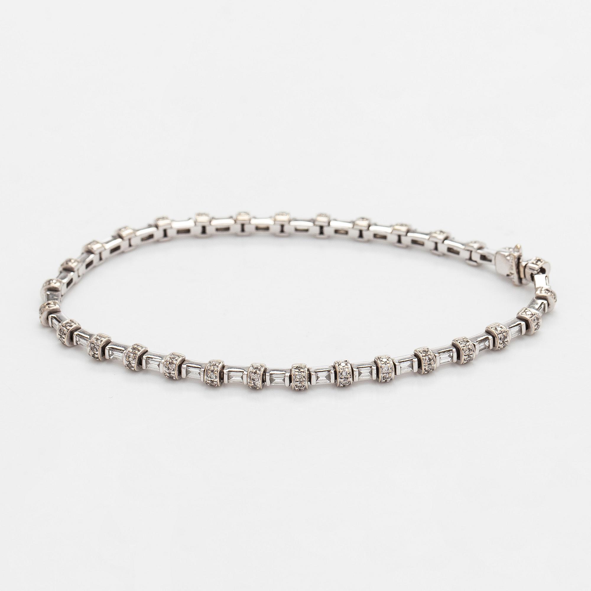 An 18K white gold bracelet set with baguette and brilliant-cut diamonds.