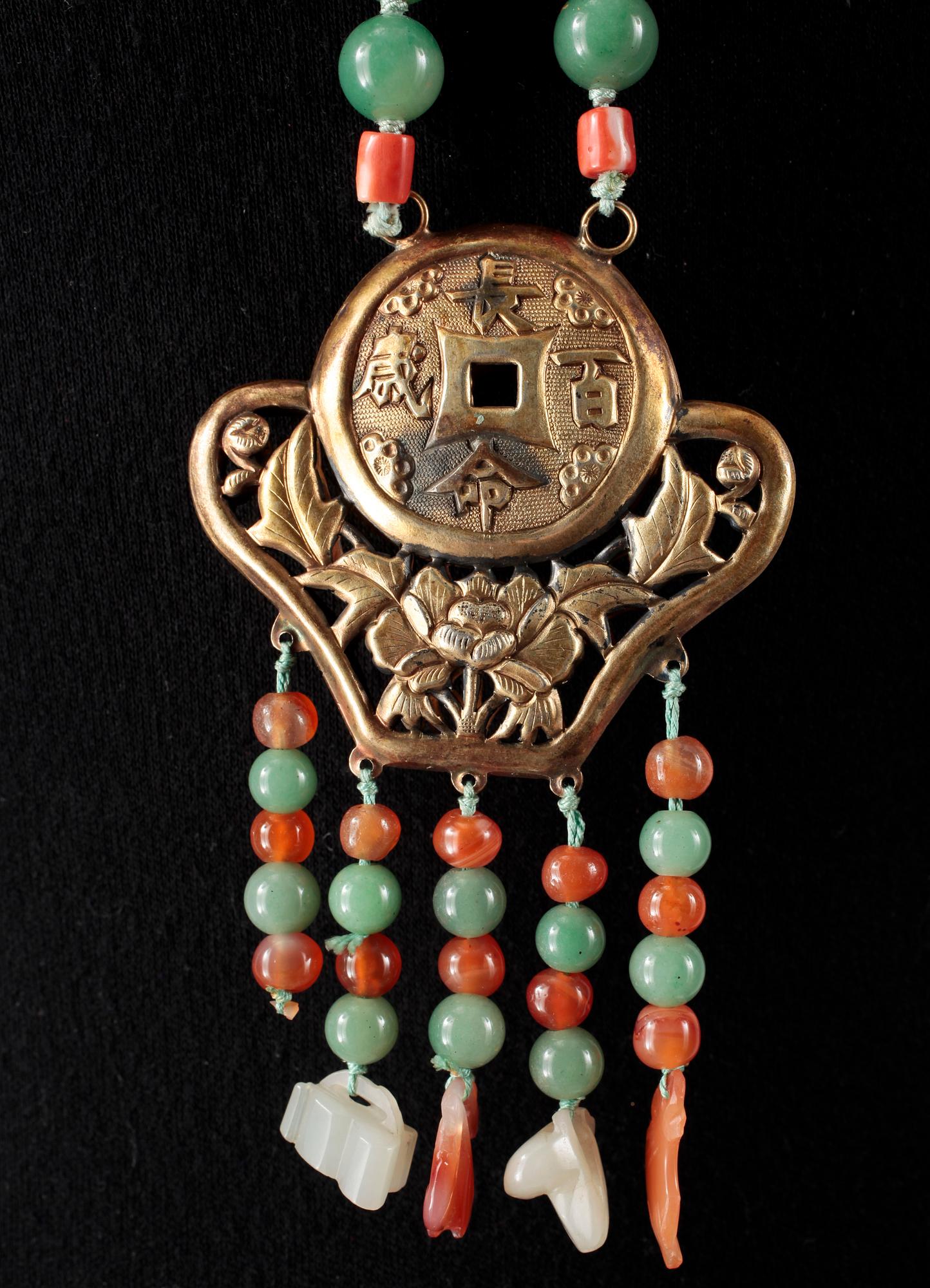 COLLIER, pärlor av bla nefrit och koraller med hänge av förgyllt silver, 1900-tal.