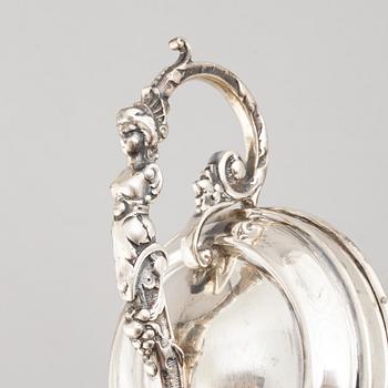 A silver bottle holder with wheels, 20th Century.