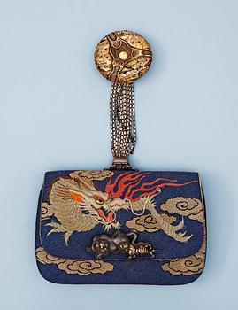 A Japanese embroided tabakoire with a kanamono in the shape of two tigers, a metal chain that holds a carved ivory manjû, second half of 19th Century. Signed.