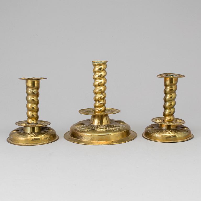 Three baroque style brass candle sticks.