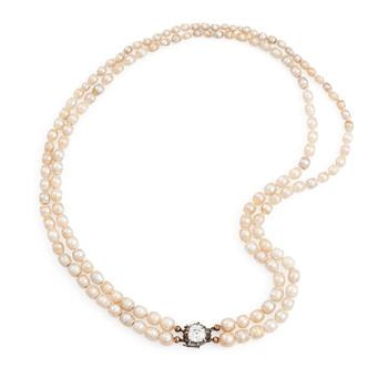 509. A two strand natural pearl necklace with a silver  clasp set with an old-cut diamond.