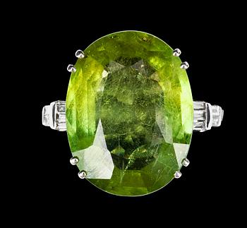 1063. A 29.50 cts peridote and diamond ring. Total carat weight of diamonds 0.60 ct.