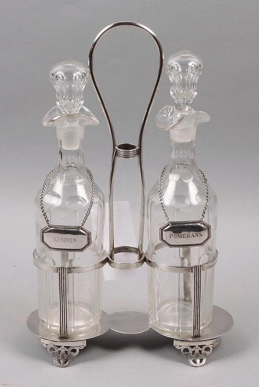 FLASKSTÄLL med FLASKOR, 2 st. Nysilver och glas. Sekelskiftet 1800/1900.