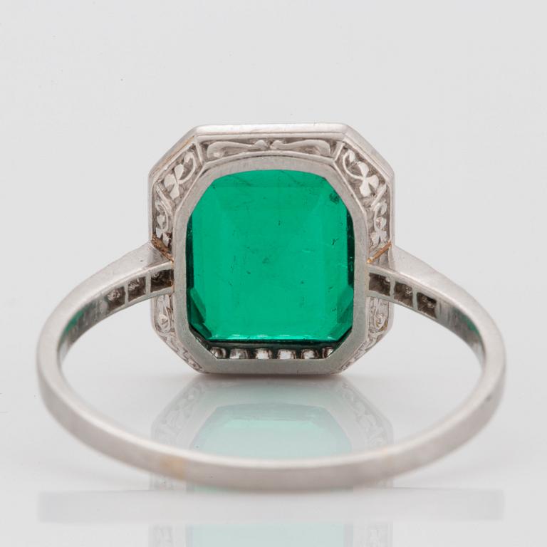 A platinum ring set with a Colombian step-cut emerald and old-cut diamonds in a fitted case from Cartier.