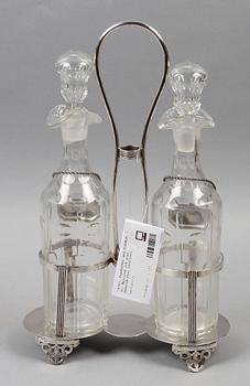 FLASKSTÄLL med FLASKOR, 2 st. Nysilver och glas. Sekelskiftet 1800/1900.