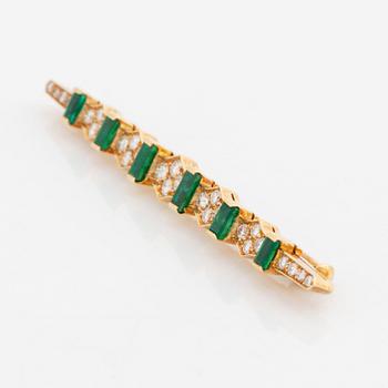 An 18K gold brooch set with step-cut emeralds and round brilliant-cut diamonds.