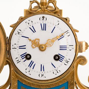 A mid-19th-century French gilt-brass mantel clock with a pair of candelabra by Dussault.