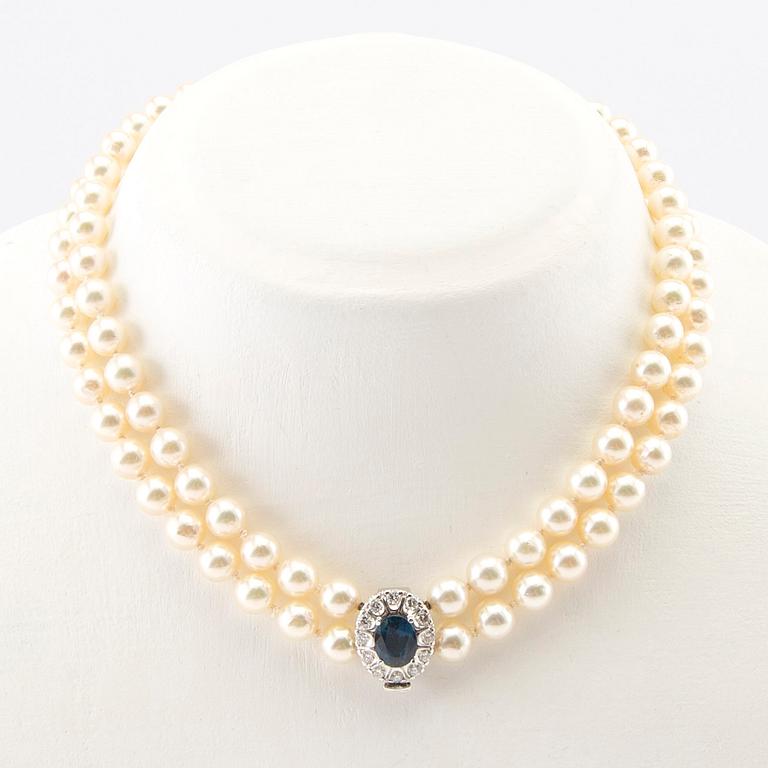 Necklace of cultured pearls with an 18K white gold clasp featuring an oval faceted sapphire and round brilliant-cut diamonds.