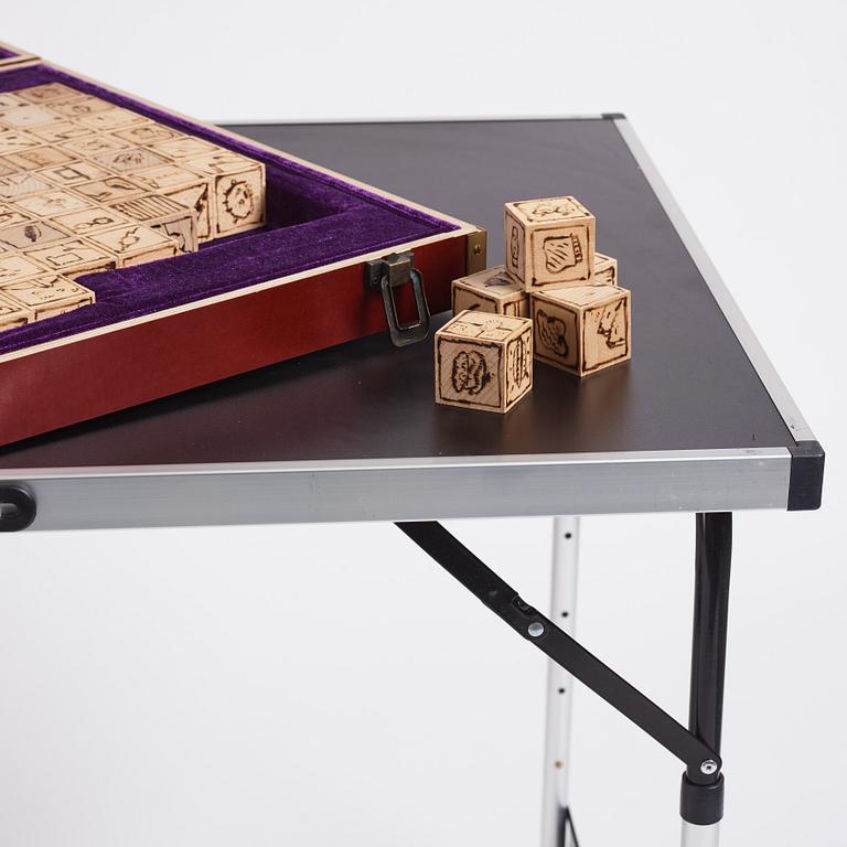 Ryan Siegan Smith. Utförd 2013. Blandteknik, trälåda, sammet, individuellt brända träklossar, ihopfällbart bord.