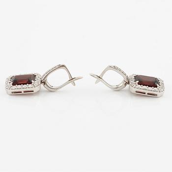 A pair of earrings in 18K white gold with faceted garnets and round brilliant-cut diamonds.