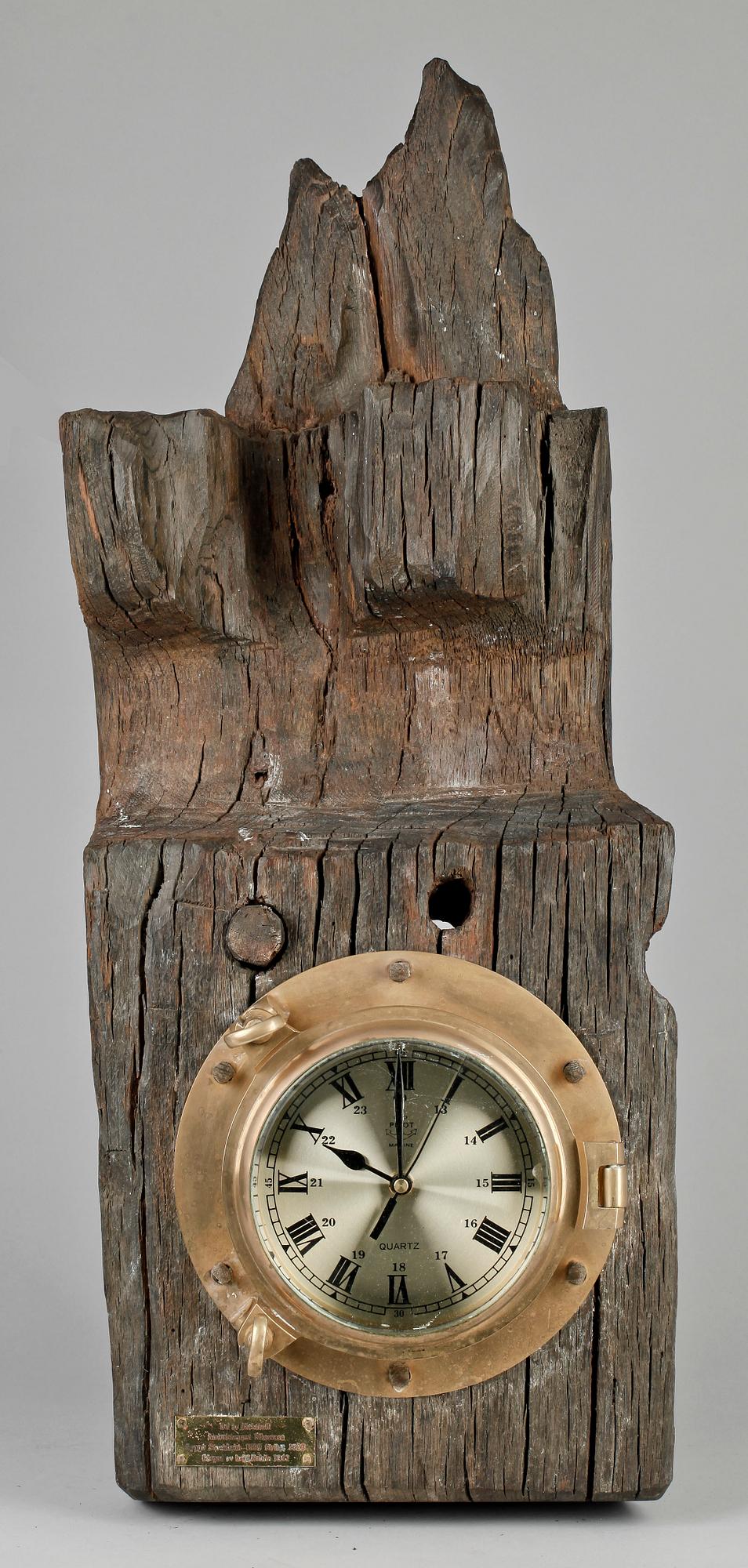 VÄGGUR innfattat i mässing på träbalk.