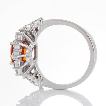 A ring set with a faceted spessartine garnet and round brilliant-cut diamonds.