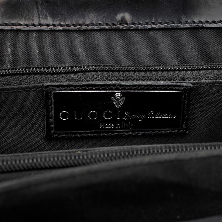 GUCCI, a black patent leather handbag.