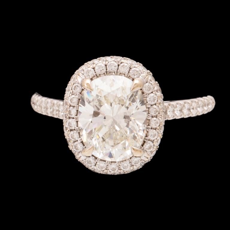 An 18K white gold ring by James Allen, set with an oval brilliant cut diamond in a halo of round brilliant cut diamonds.