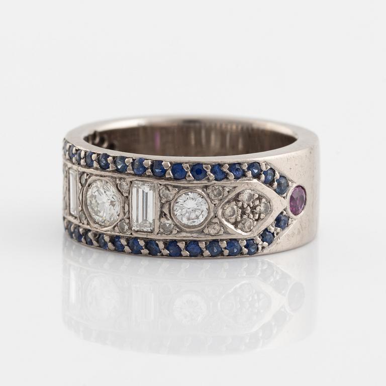An 18K white gold ring set with diamonds, rubies and sapphires.