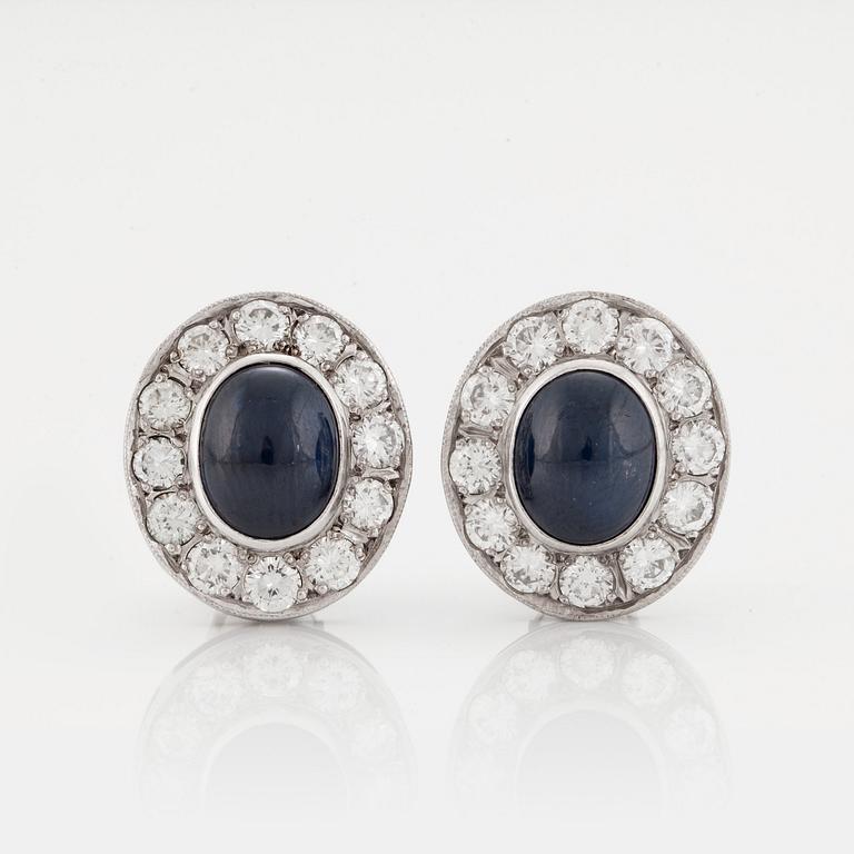 A pair of earrings set with cabochon-cut sapphires and round brilliant-cut diamonds.