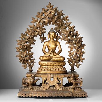 474. A large Nepalese gilt bronze buddha on a throne with mandorla, 18/19th Century.