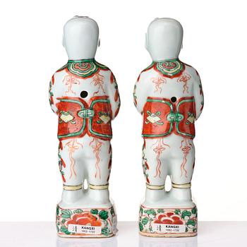 A pair of wucai decorated porcelain figurines of boys with flowers, Qing dynasty, Kangxi (1662-1722).