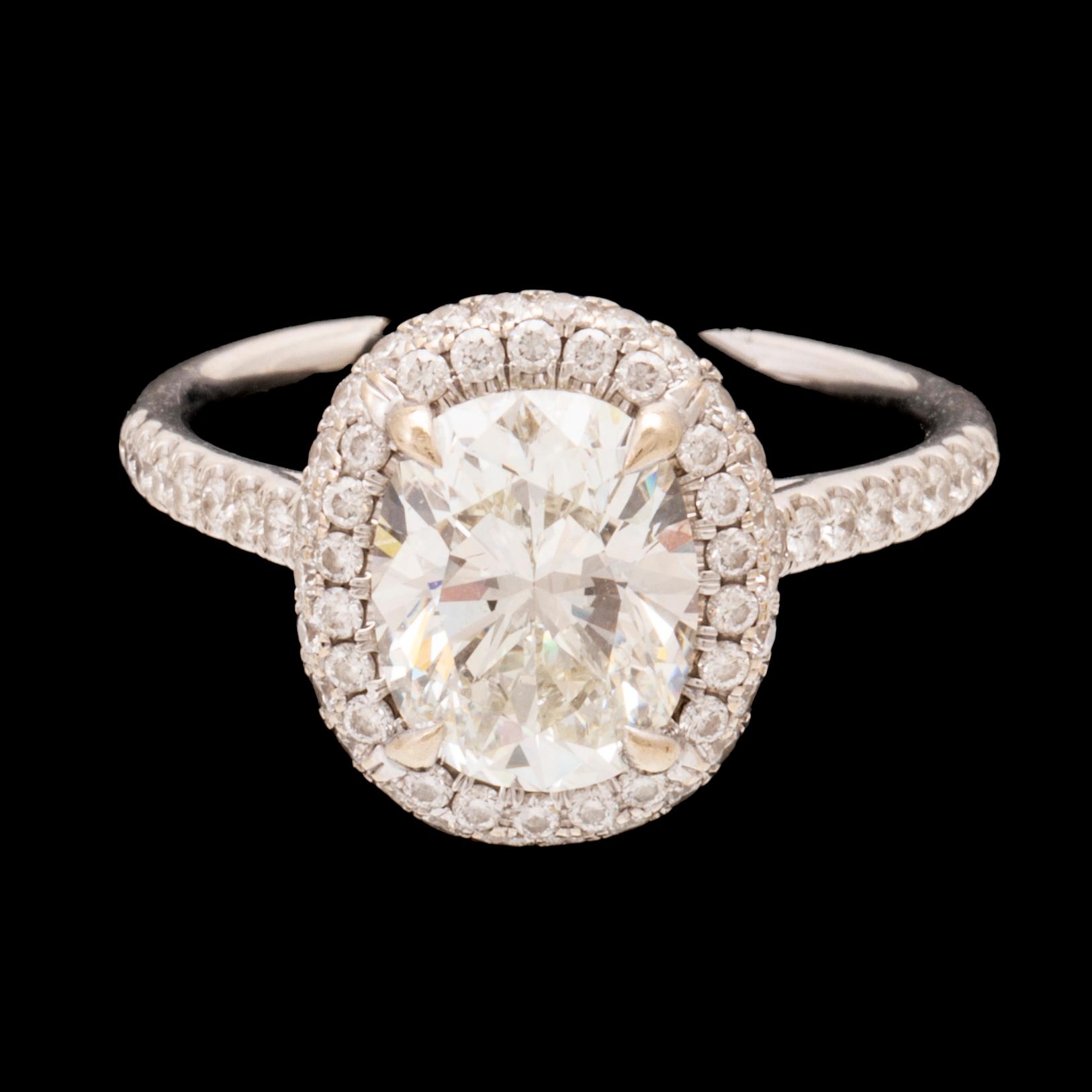 An 18K white gold ring by James Allen, set with an oval brilliant cut diamond in a halo of round brilliant cut diamonds.