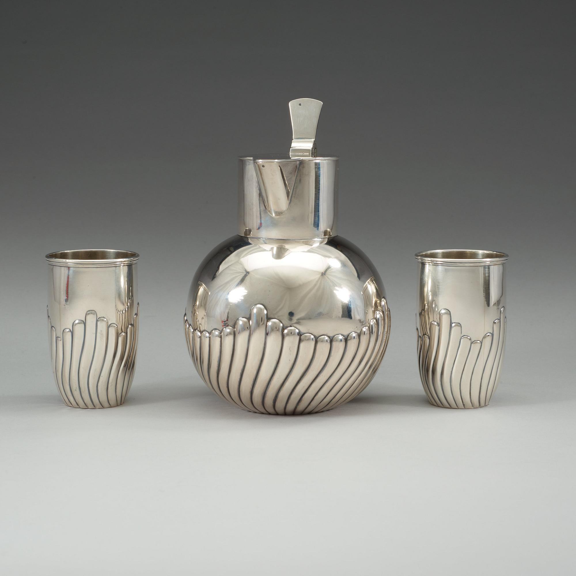 A Russian early 20th century parcel-gilt wine-jug and a pair of beakers, unidentified makers mark, St. Petersburg.