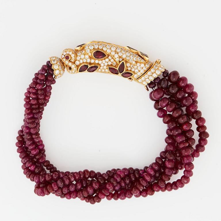 A Cartier chimera head bracelet in 18K gold set with round brilliant-cut diamonds and faceted rubies.