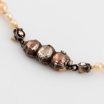 A pearl necklace with a silver and gold clasp set with rose-cut diamonds.