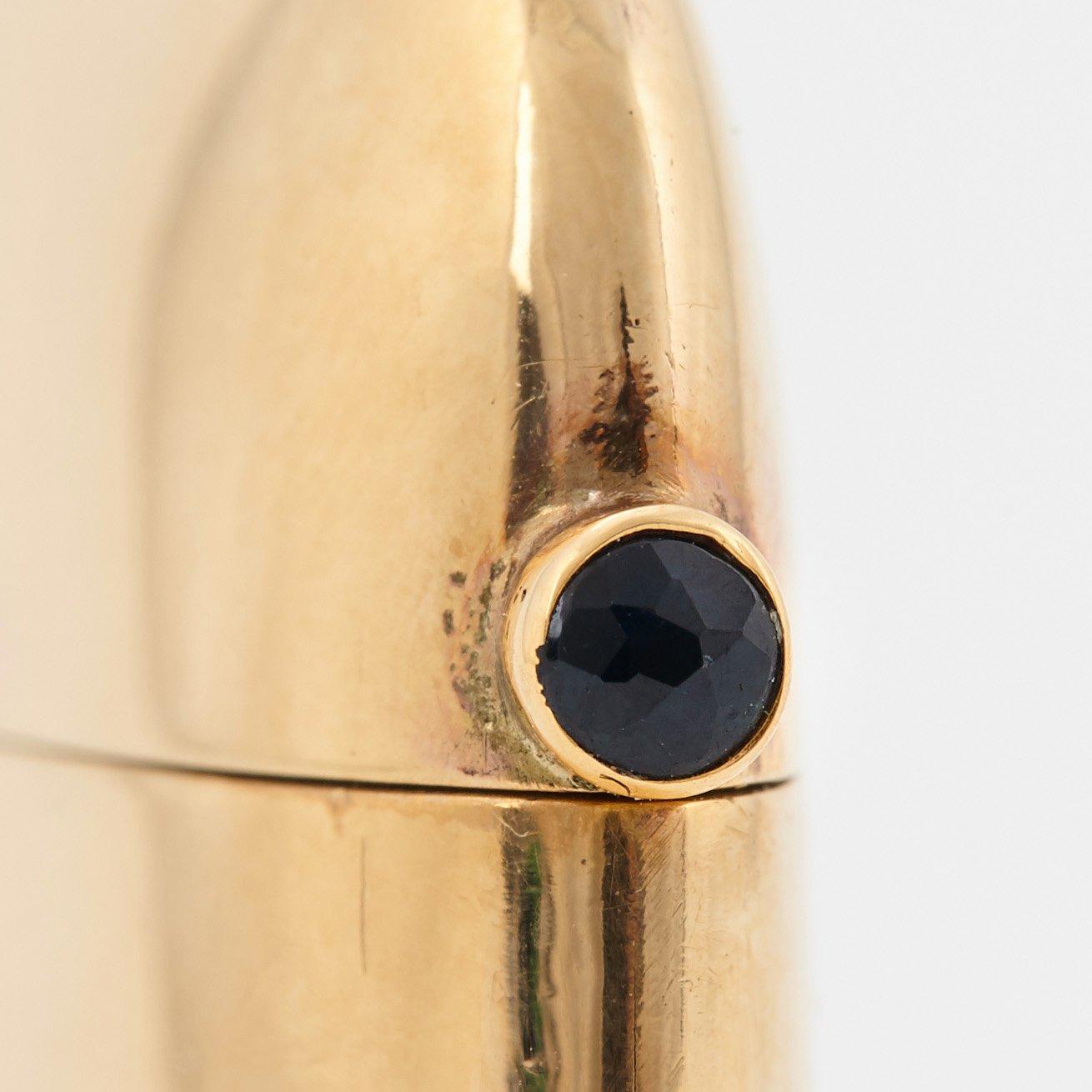 An 18K gold match case/pendant set with a faceted sapphire.