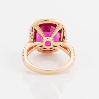 An 18K gold ring set with a faceted pink tourmaline and round brilliant-cut diamonds.