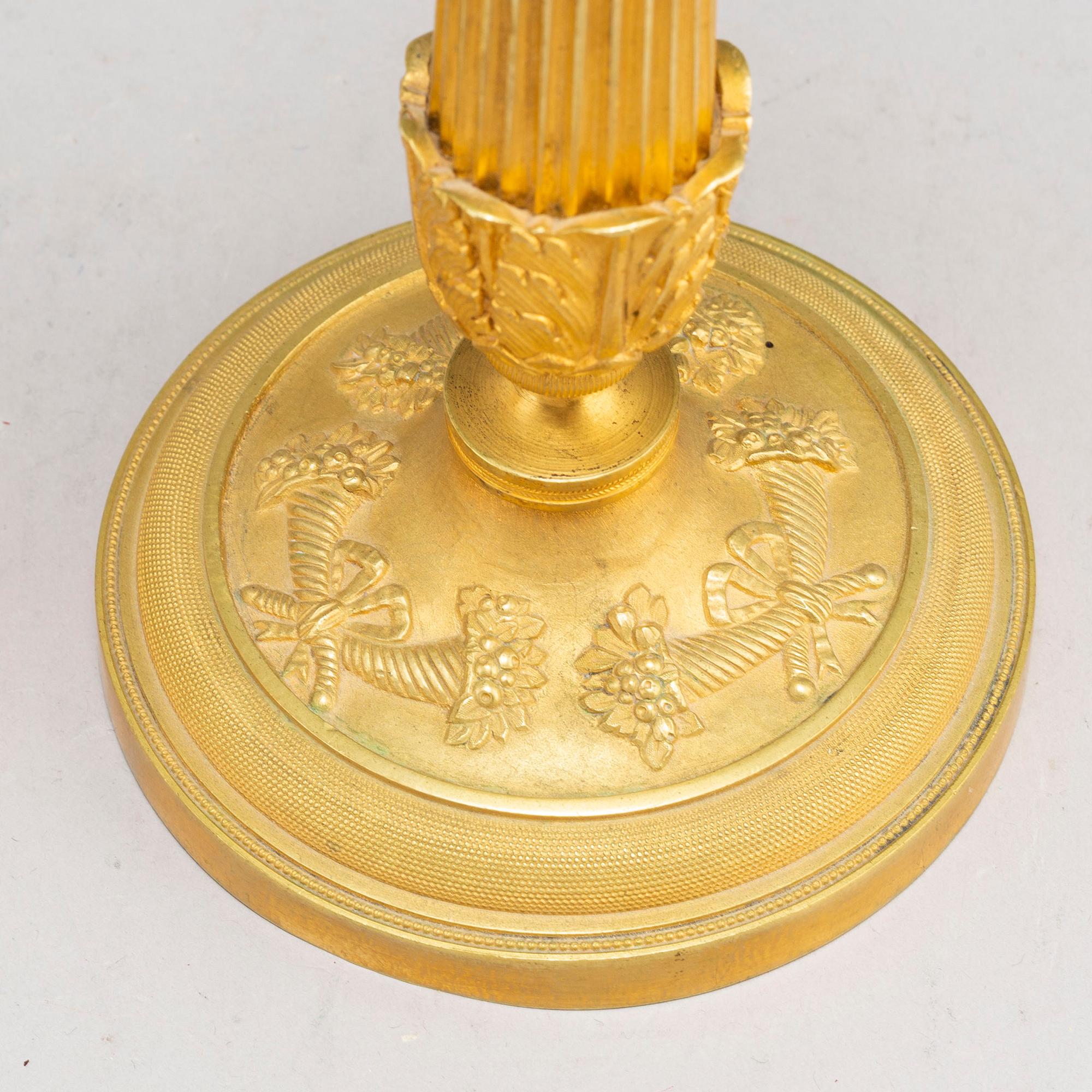 A pair of first half of the 19th century Empire candel sticks, gilded bronze, first half of the 19th century.