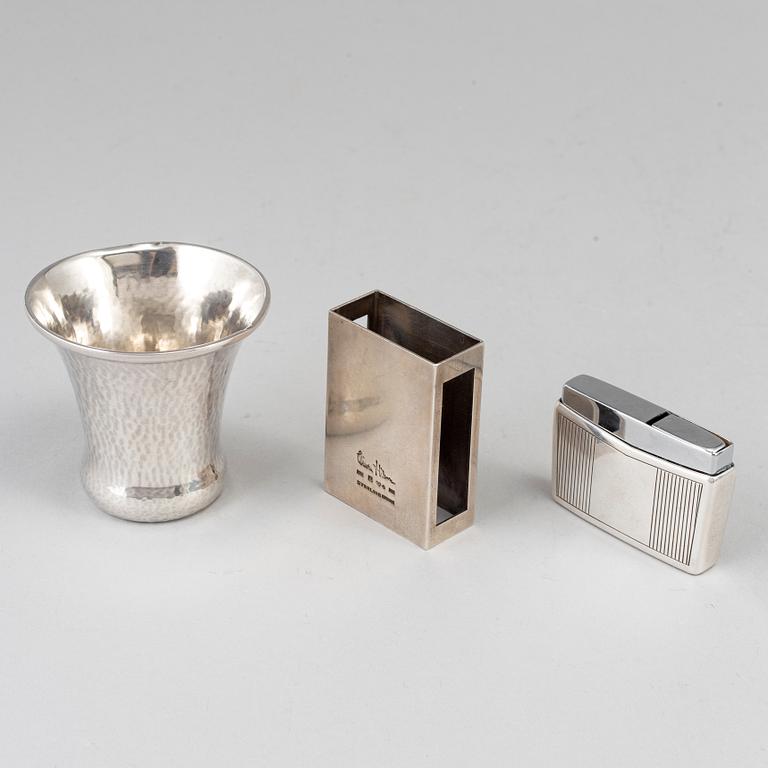 A silver vodkacup, lighter and matchholder.