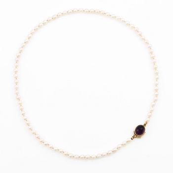 Necklace of cultured pearls with an oval cabochon-cut amethyst clasp in 18K gold.