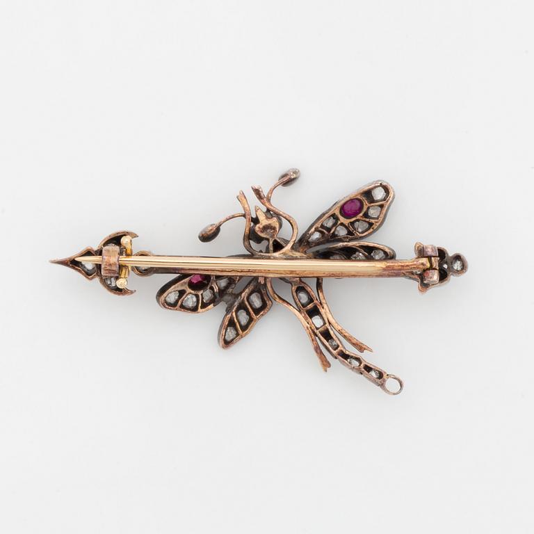 A silver and gold brooch set with rose-cut diamonds and cabochon-cut rubies.