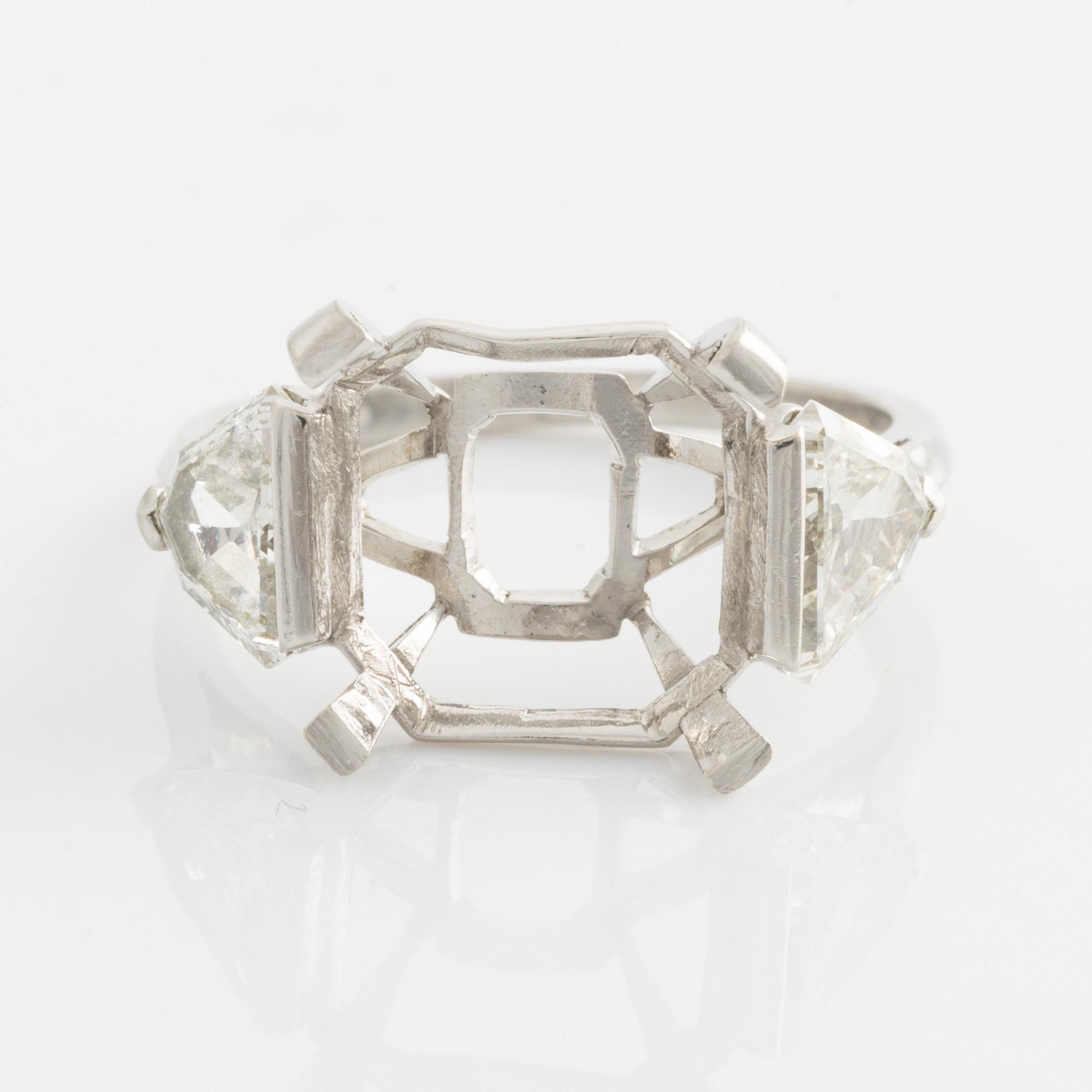 A platinum ring with and empty setting and with two triangular step cut diamonds.