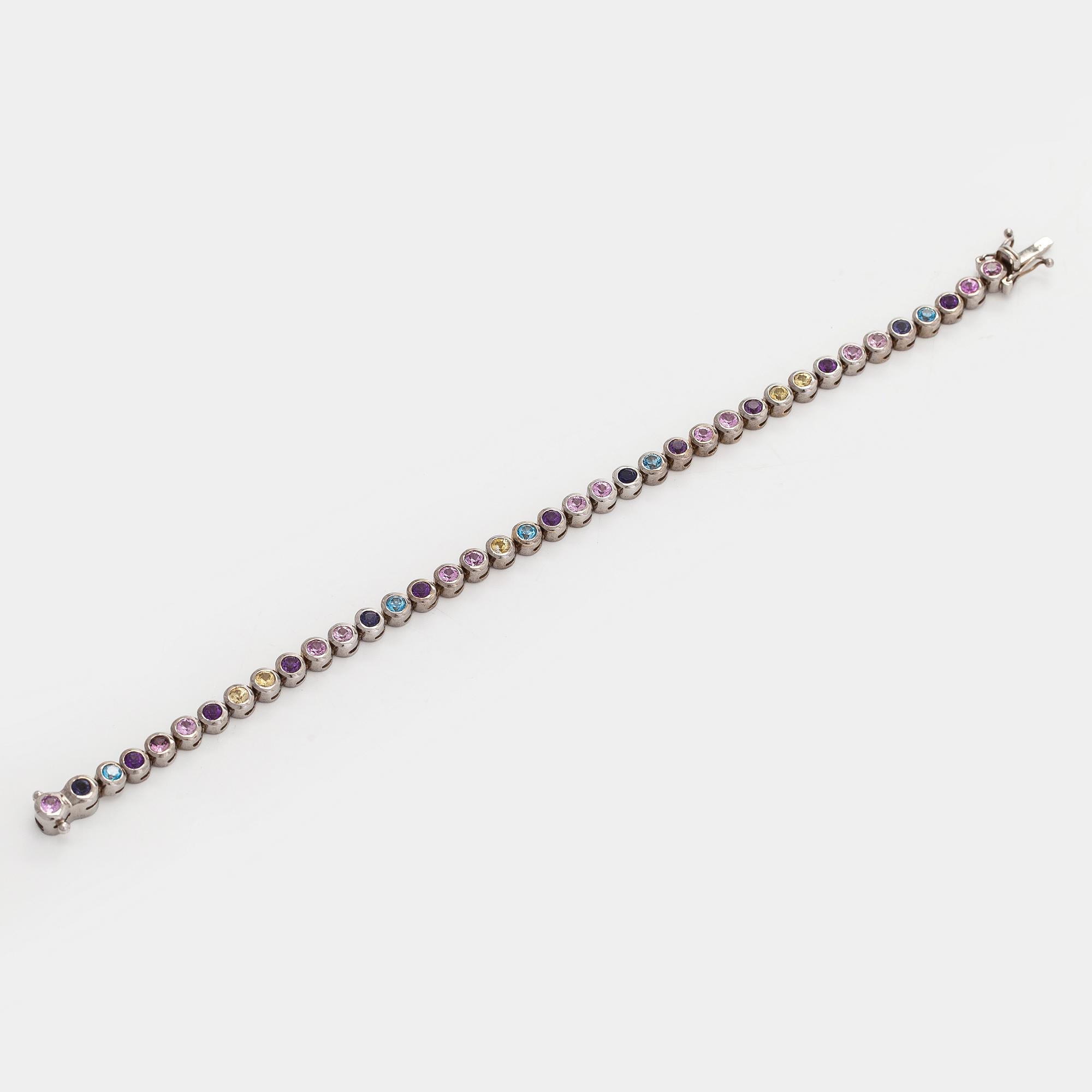 Rannekoru, 18K valkokultaa ja monivärisiä kiviä.